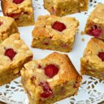 Doily covered tray of white chocolate and raspberry blondies.
