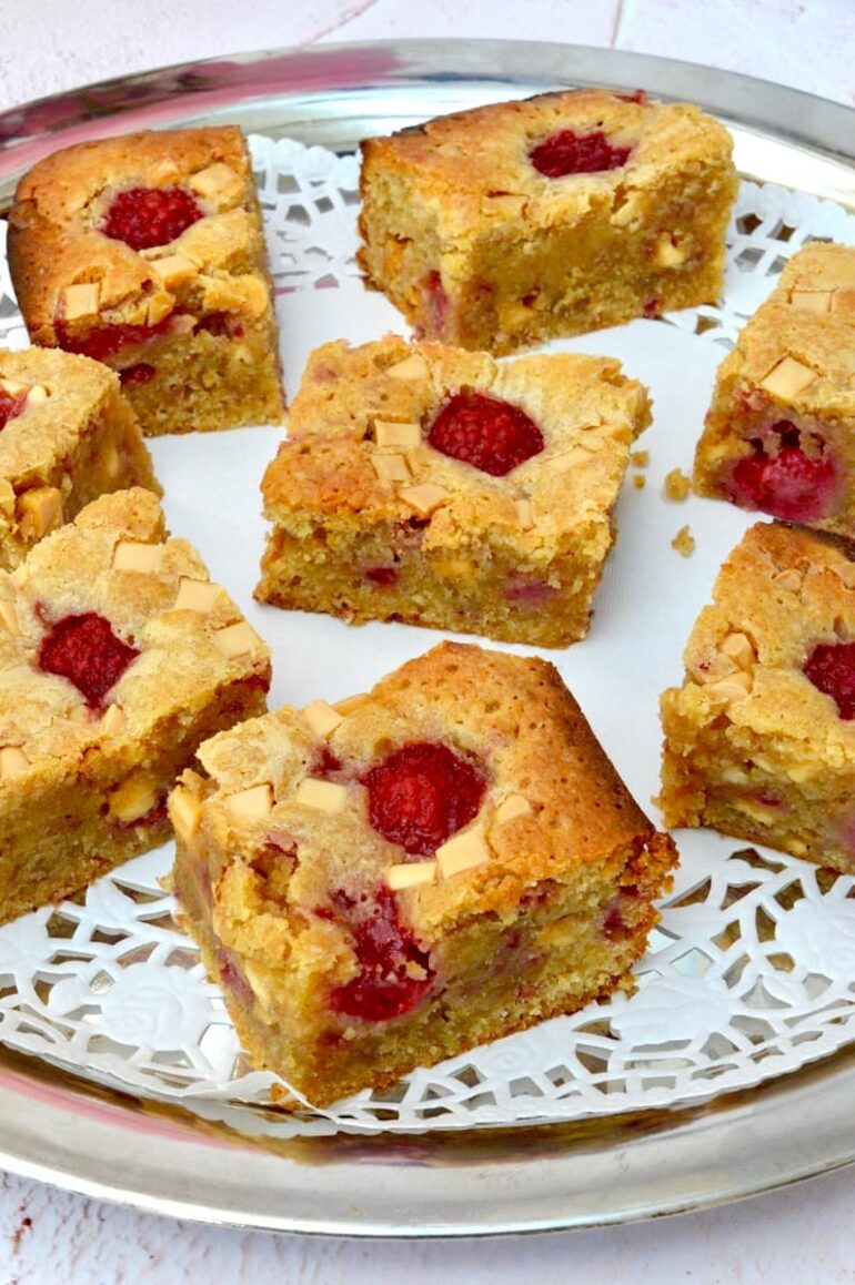 A doily covered tray of white chocolate and raspberry blondies.