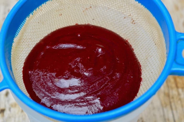 Blackberry purée in sieve.