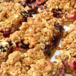 Close up of a plate of blackberry and apple crumble bars.