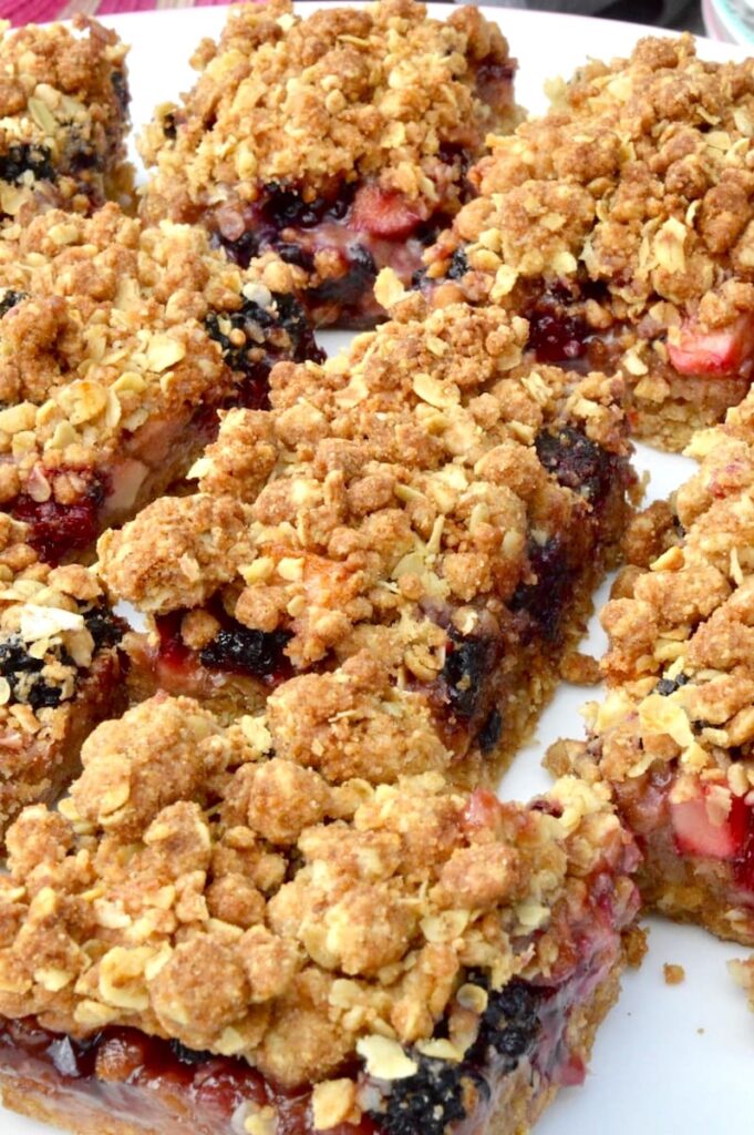 A close up of a plate of blackberry and apple crumble bars.