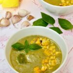 Two bowls of courgette and corn soup with dollop of vegan basil pesto and roasted sweetcorn on top.