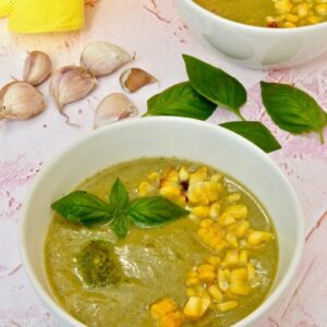 Two bowls of courgette and corn soup with a dollop of vegan basil pesto and roasted sweetcorn scattered over the top.