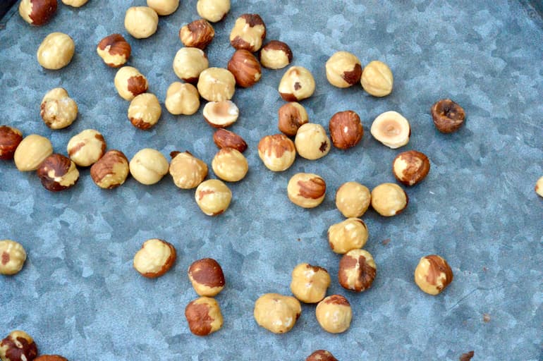 Skinned roasted hazelnuts scattered on a tray.