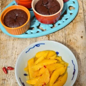 Four individual Mexican chocolate pudding with a bowl of chilli & lime mango slices.