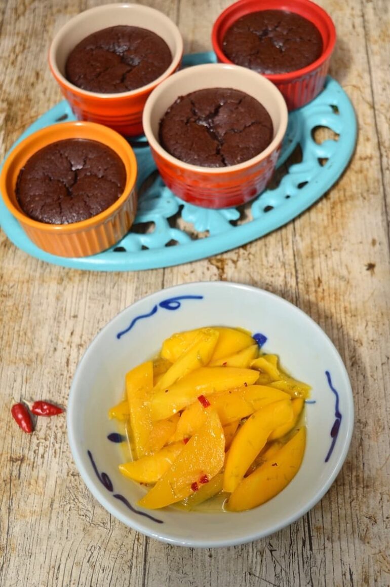 Four individual Mexican chocolate pudding with a bowl of chilli & lime mango slices.