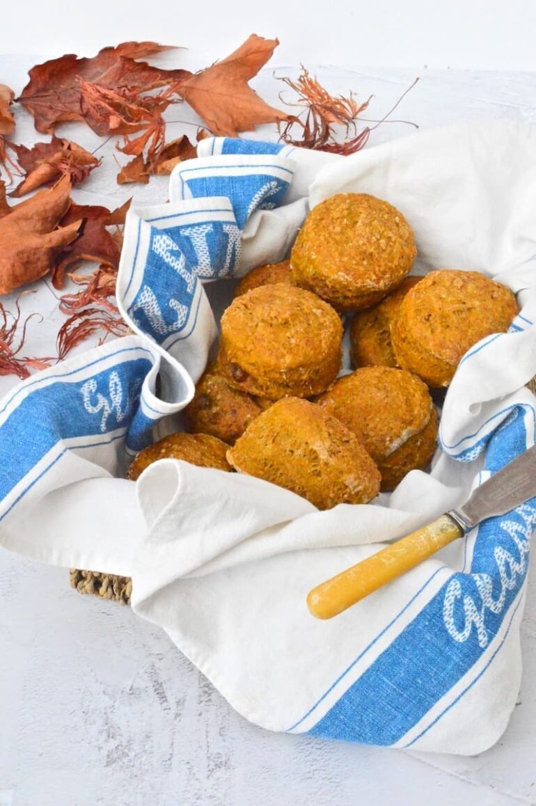 A basket of healthy vegan pumpkin scones surrounded by autumn leaves.