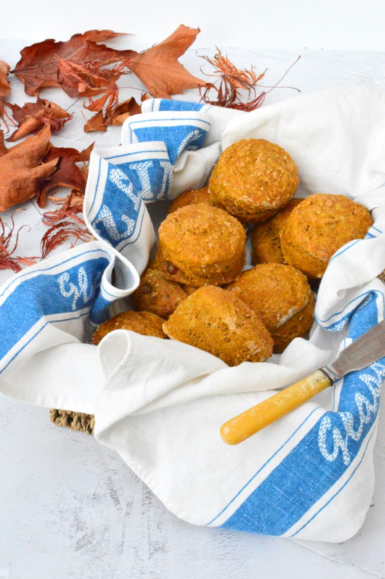 Basket of healthy vegan pumpkin scones surrounded by autumn leaves.