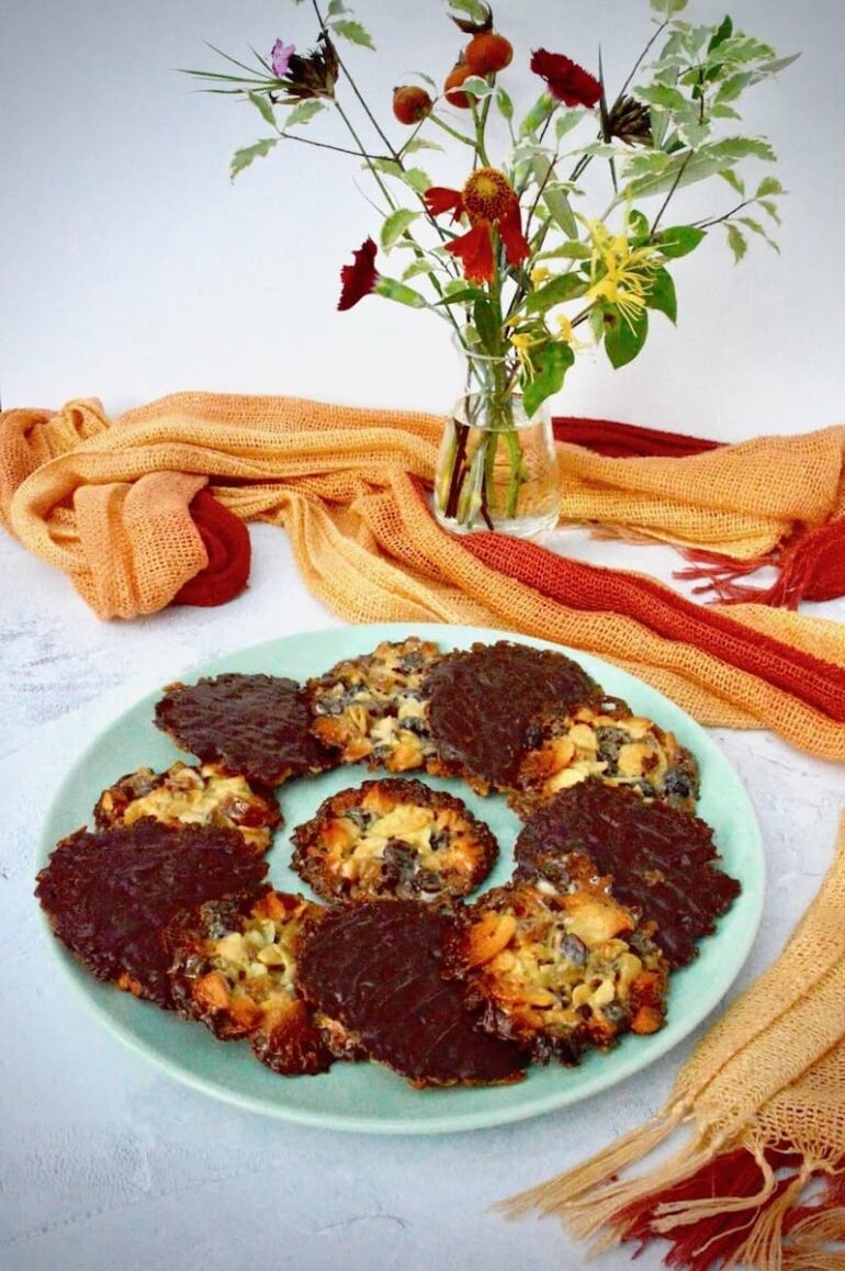 A blue plate of Nigella's florentines with a vase and scarf in the background.