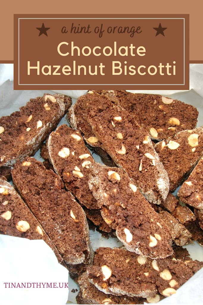 Chocolate, hazelnut biscotti in a tin lined with greaseproof paper. Text box reads " a hint of orange chocolate hazelnut biscotti".