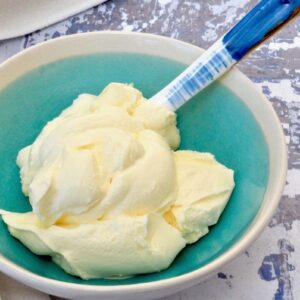 A turquoise bowl of homemade crème fraîche with blue spoon.
