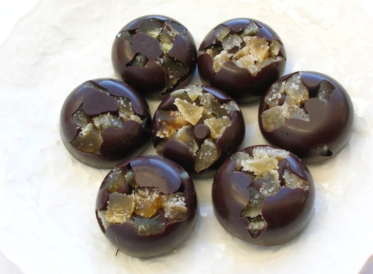 Seven round homemade ginger chocolates sitting on a white plate.