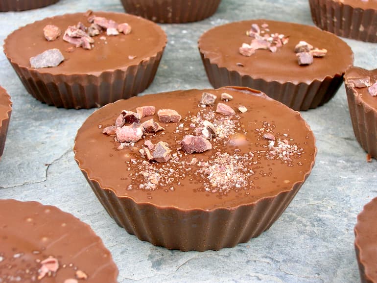 Homemade chocolate peanut butter cups topped with chips of cacao nibs.
