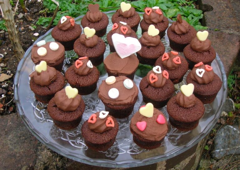 A batch of chocolate Valentine's cakes covered in whipped chocolate ganache and decorated with various edible hearts.
