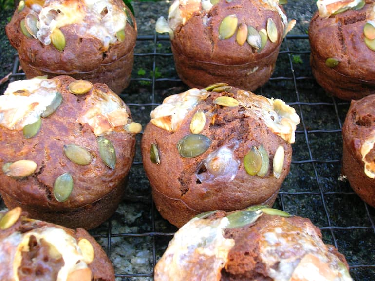 A batch of savoury pumpkin muffins with toasted goat's cheese and pumpkins seeds on top.