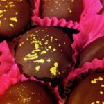 Rosemary chocolate truffles decorated with edible glitter nestled in bright pink paper cases.
