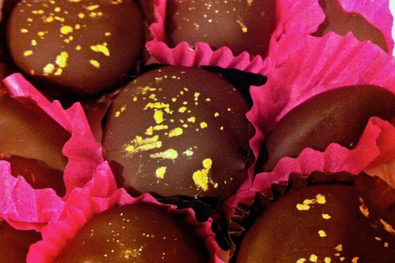 Rosemary chocolate truffles decorated with edible glitter nestled in bright pink paper cases.