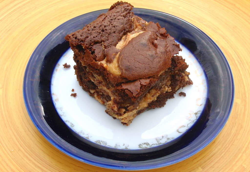 A healthier cashew nut butter brownie sitting on a blue rimmed plate.