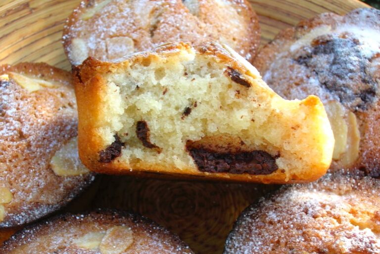 Close up of a bamboo platter with five cinnamon chocolate chip friands and a half one balanced on top.