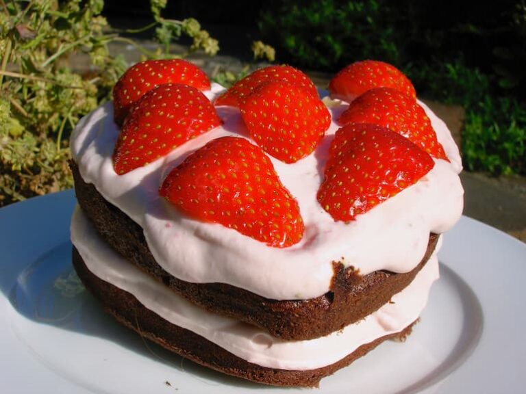 Heart shaped chocolate cake with strawberry cream and sliced strawberries.