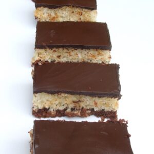 A row of homemade chocolate coconut bars on a white tray.