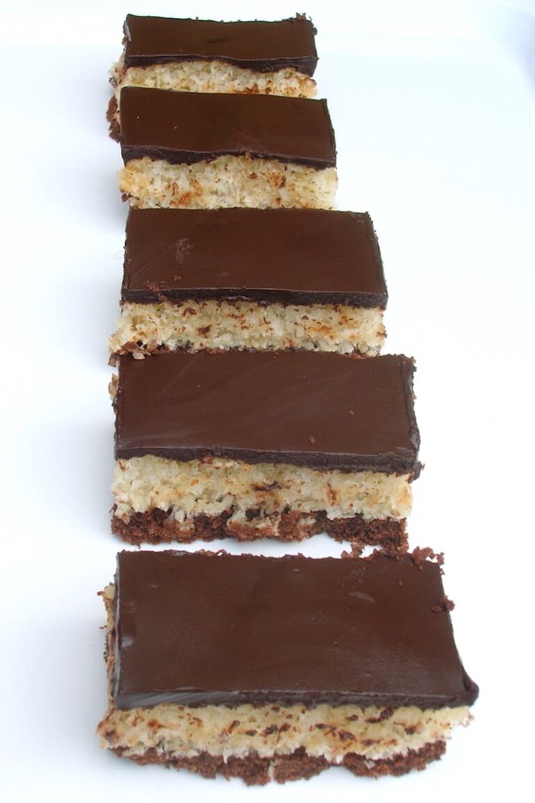 A row of homemade chocolate coconut bars on a white tray.