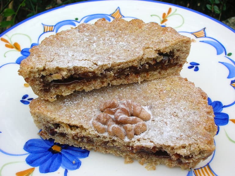 Two halves of a walnut pastry filled with chocolate spread.