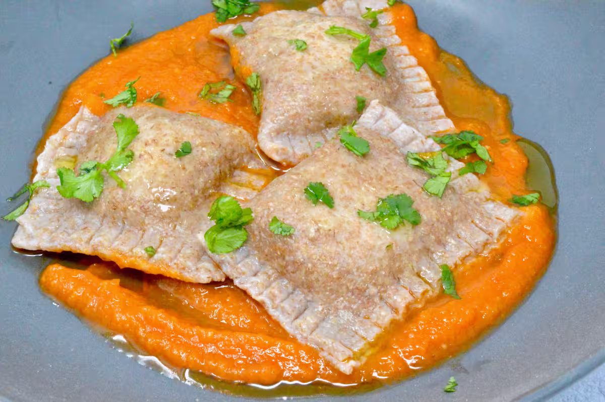 Homemade vegan ravioli with a mushroom and lentil filling on a bed of tomato sauce.