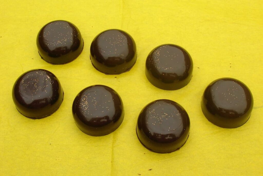 Seven homemade passionfruit caramel chocolates on a yellow cloth.