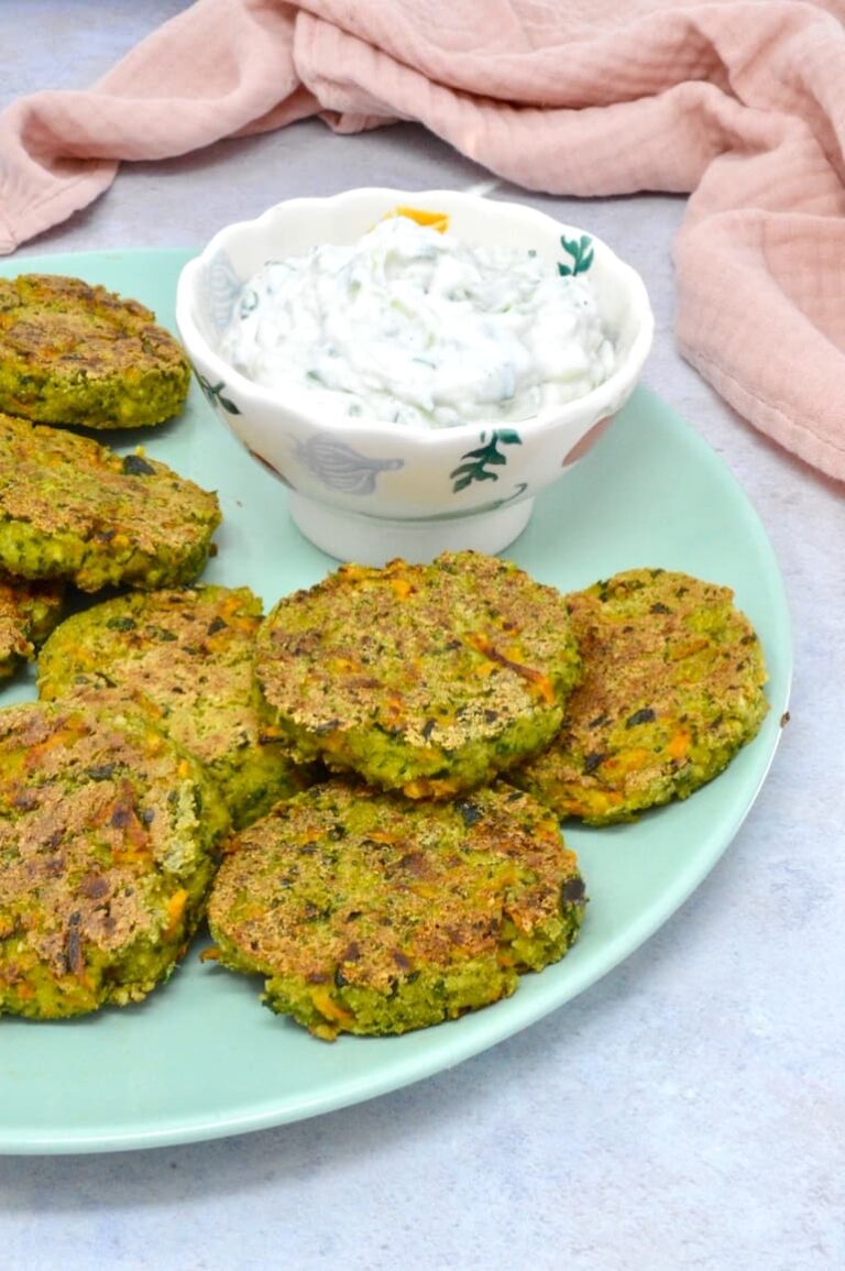 A turquoise plate of vegan wild garlic tofu patties and a bowl of vegan tzatziki. A pink cloth in the background.