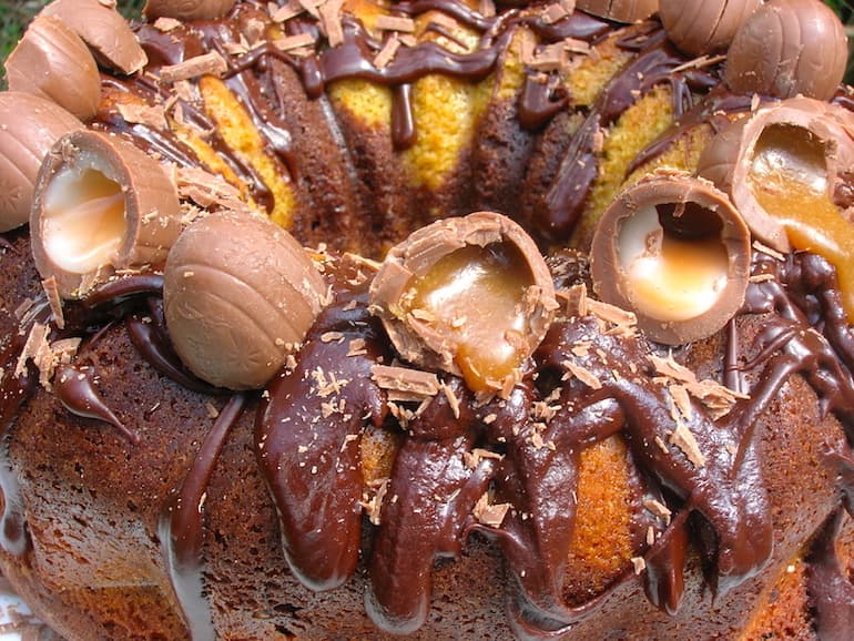 A close up of halved mini Easter creme eggs sitting on top of a chocolate orange bundt cake.