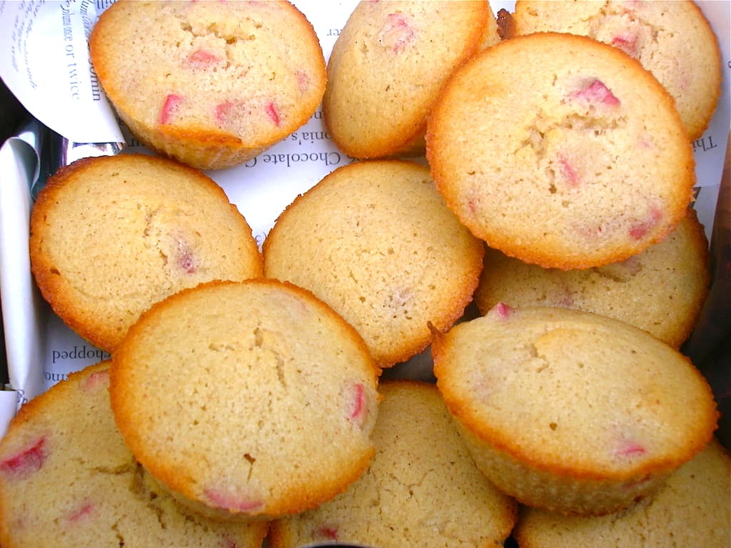Close up of a pile of white chocolate rhubarb friands in an open tin.