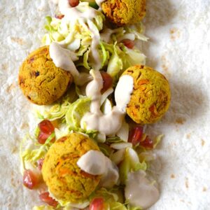 Air fryer carrot falafel on flat bread with salad and tahini sauce.