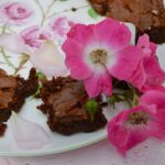 Rose cardamom brownies on a rose patterned plate with fresh roses.