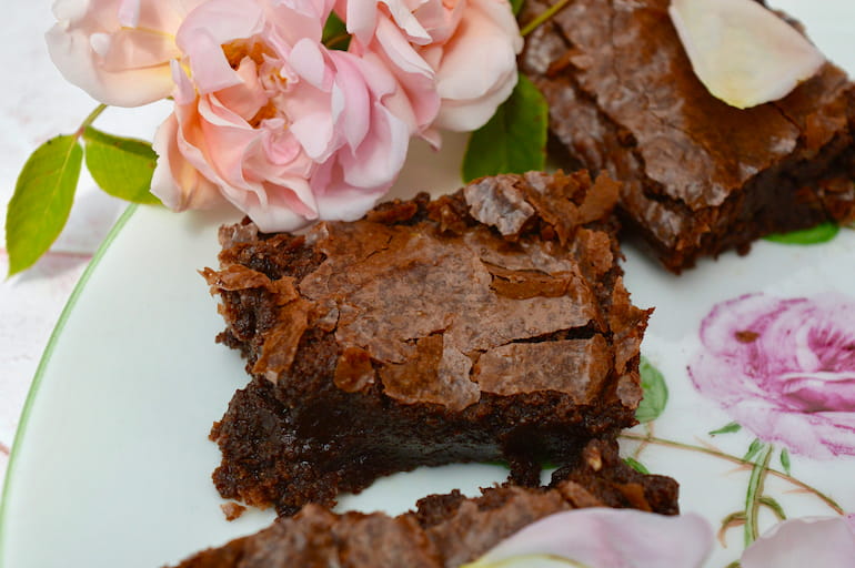 Close up of rose cardamom brownies on a rose plate with fresh roses.