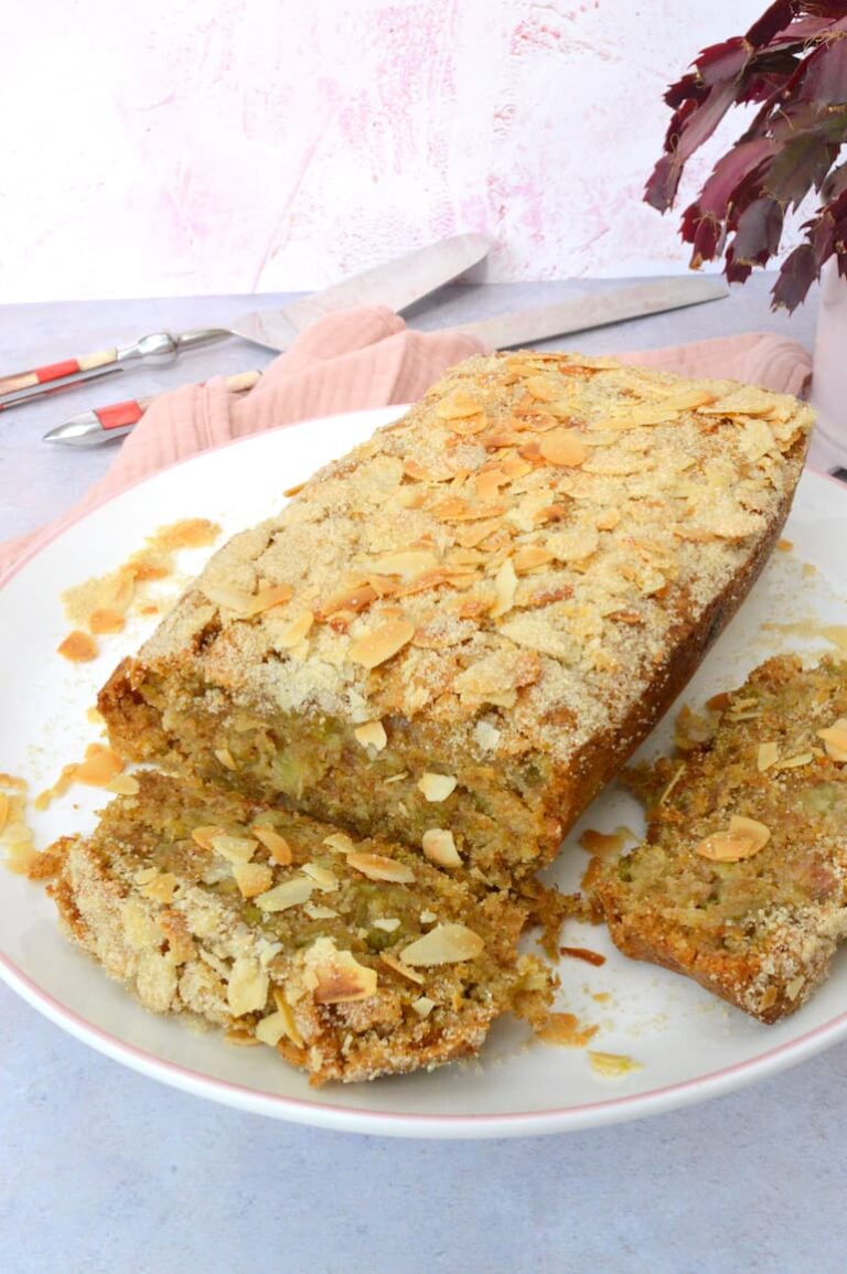 Vegan almond rhubarb loaf cake and two slices on a cake stand.