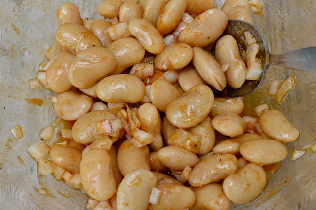 Butter beans and chopped onions mixed into a Spanish salad dressing.