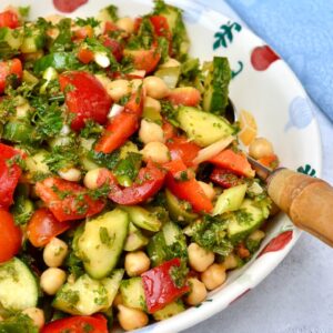 A bowl of Middle Eastern chickpea salad with a blue cloth in the background.