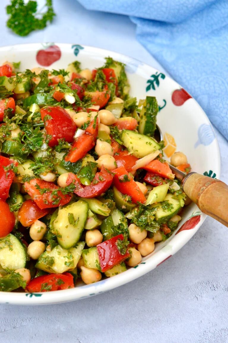 A bowl of Middle Eastern chickpea salad with a blue cloth in the background.