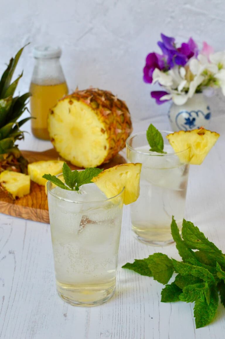 Two glasses of pineapple shrub diluted with ice and sparkling water.