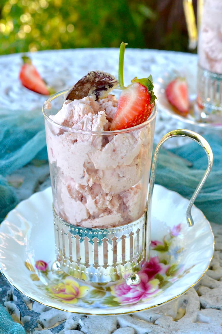 A glass of roasted strawberry ice cream with strawberry on top.
