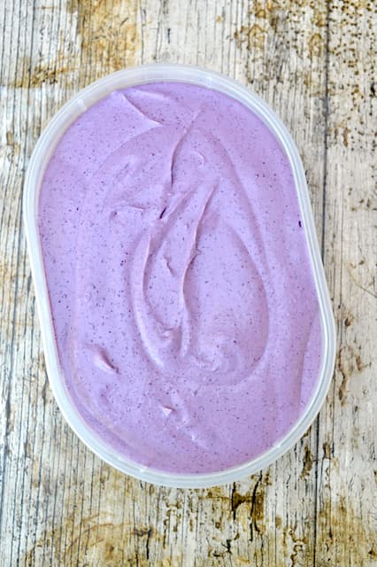 A tub of yet to be frozen homemade blackberry ice cream.