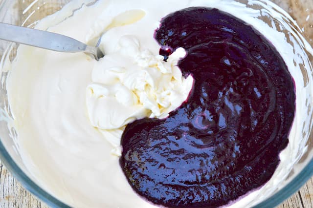 A bowl of whipped cream and unmixed berry purée.