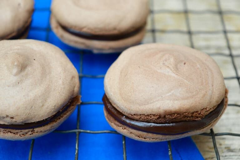 Four chufa chocolate macaroons filled with honeyed chocolate ganache on a wire rack.
