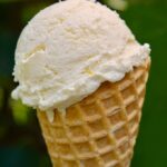 A scoop of easy peasy lemon squeezy ice cream in a cone.