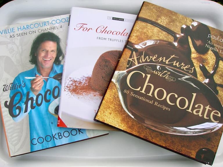 Three chocolate cookbooks laid out flat but overlapping each other a little.