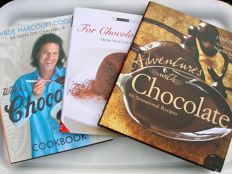 Three chocolate cookbooks laid out flat but overlapping each other a little.