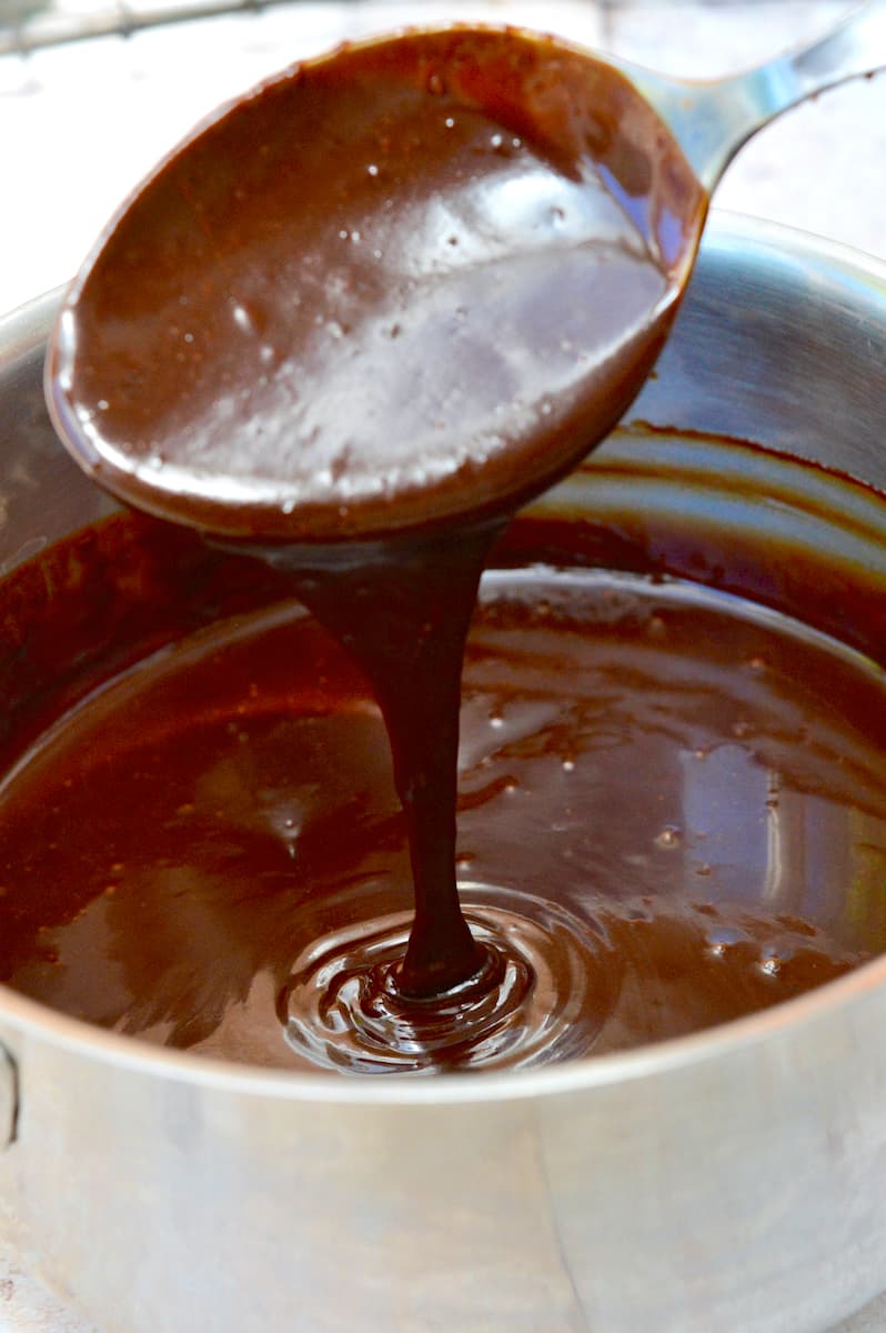 Chocolate water ganache pouring into a pan from a spoon.