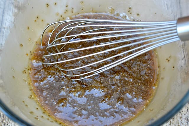 Sugar, oil and a chia egg in a bowl with whisk.