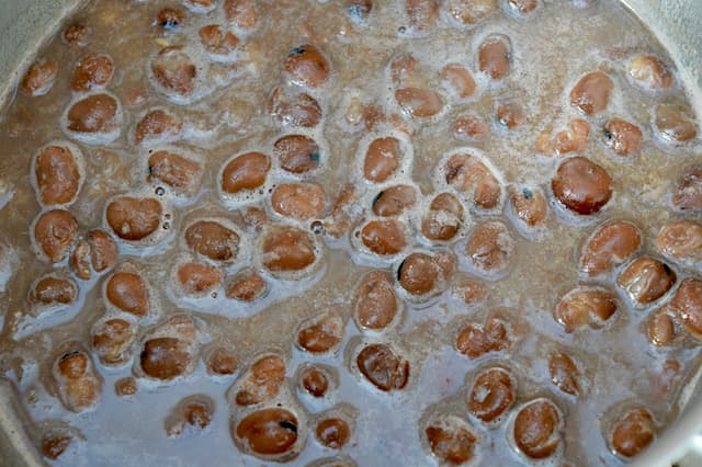 Fava beans simmering in a pan of water.